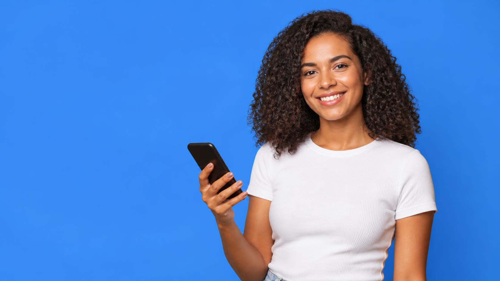 Smiling woman holding a smartphone against a blue background
